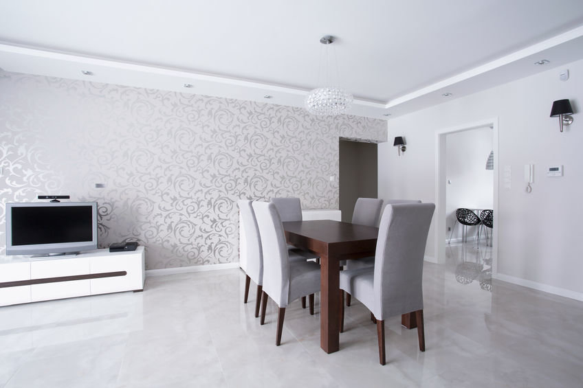 Modernes Wohnzimmer mit Esstisch und Stühlen sowie Bord mit Ferseher vor einer mit floralem Tapetenmuster tapezierten Wand