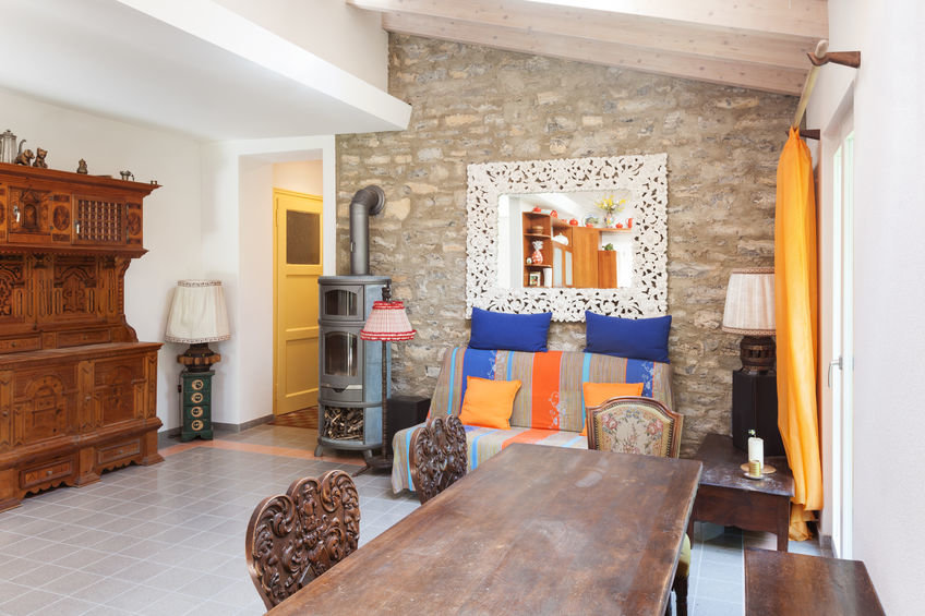 Gemütlich eingerichtetes Zimmer mit kleinem Kaminofen an der mit Naturstein verblendeten Wand